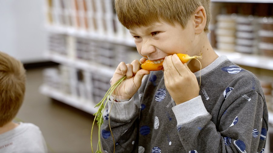 Still from the CCFE film: a child tasting a fresh carrot