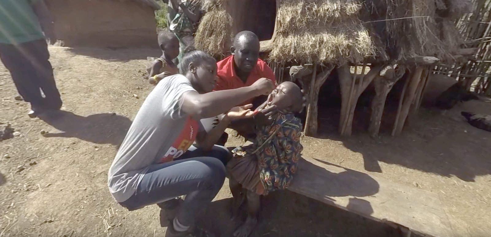 A health worker gives two drops of oral polio vaccine to a child — the purpose of the whole journey