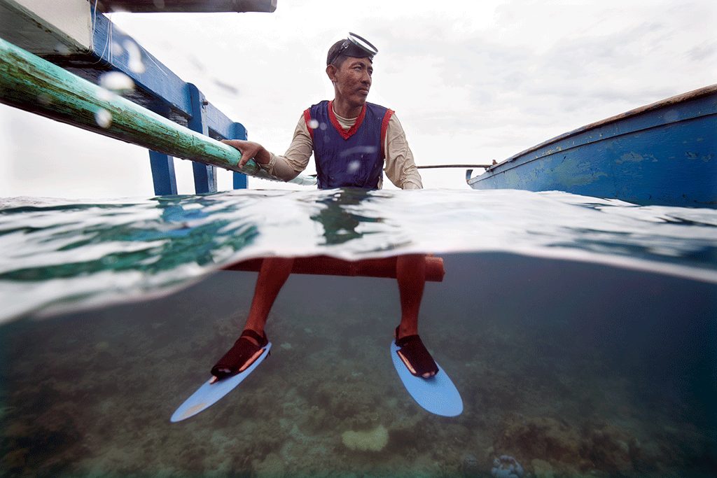 A free-diver at the surface beside his outrigger boat