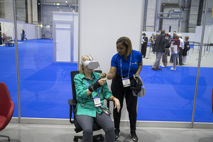 A Rotary volunteer guiding a delegate into a VR headset for the first time