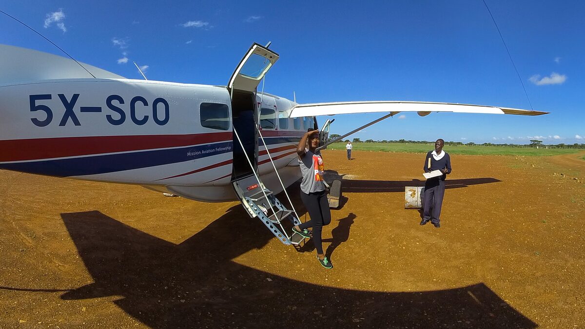 Patience steps off a bush plane onto a remote dirt airstrip