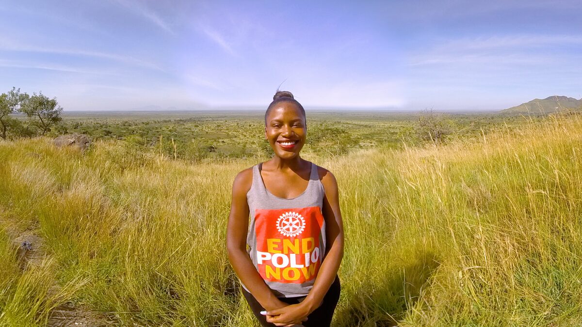 Patience Asiimwe in the grasslands, wearing an End Polio Now shirt