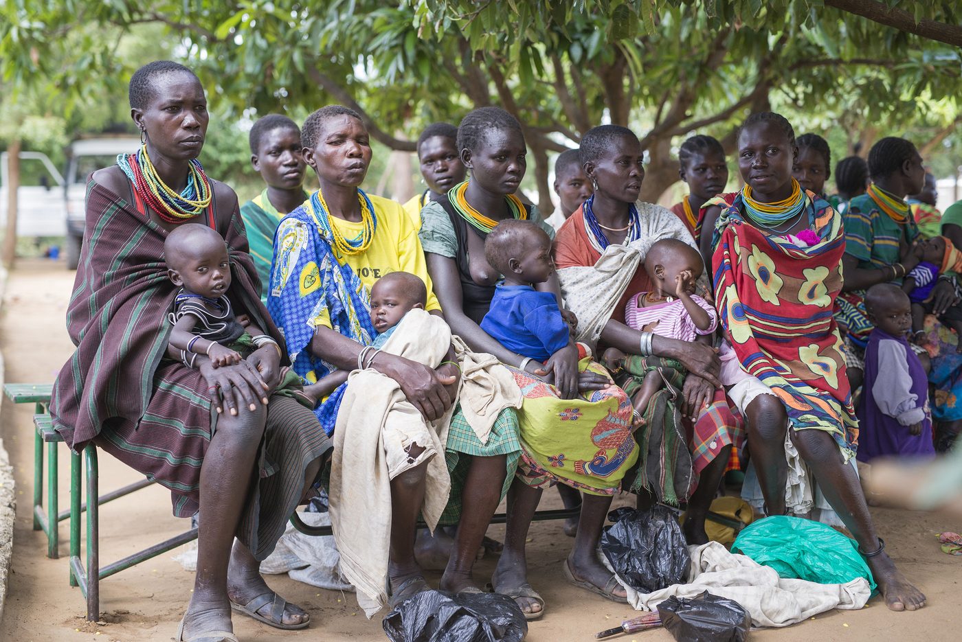 A row of Karamojong mothers holding their babies while waiting for a weekly outpatient feeding program