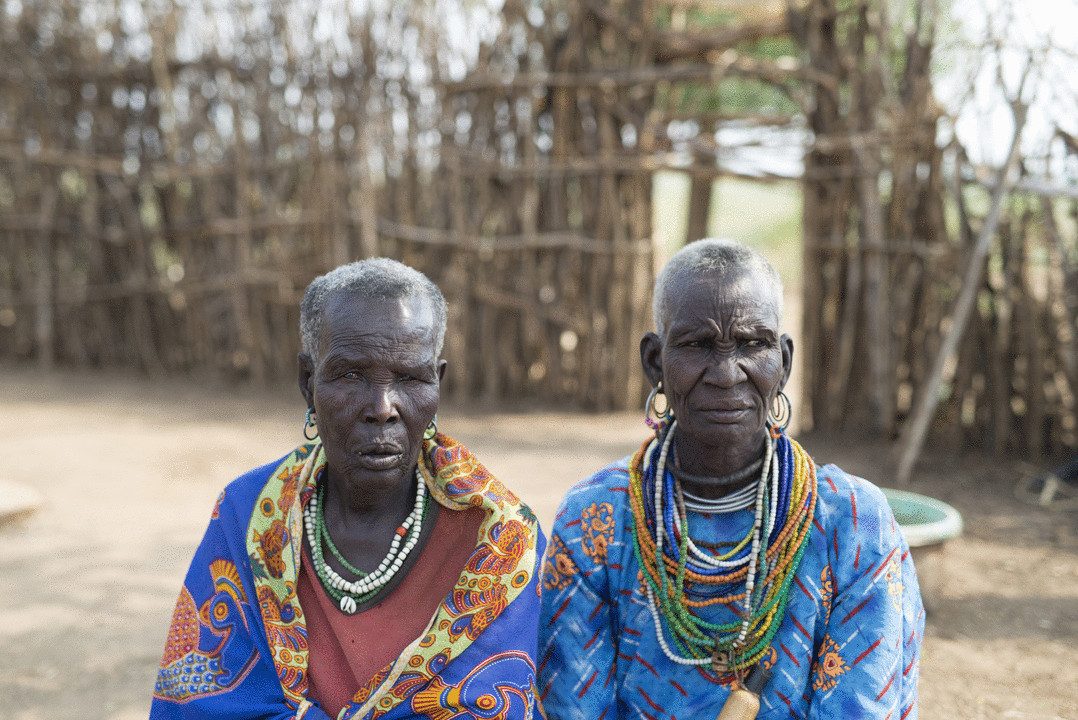 Lochap's grandmothers, aged 73 and 95, seated together outside their home in the Karamoja region of Uganda
