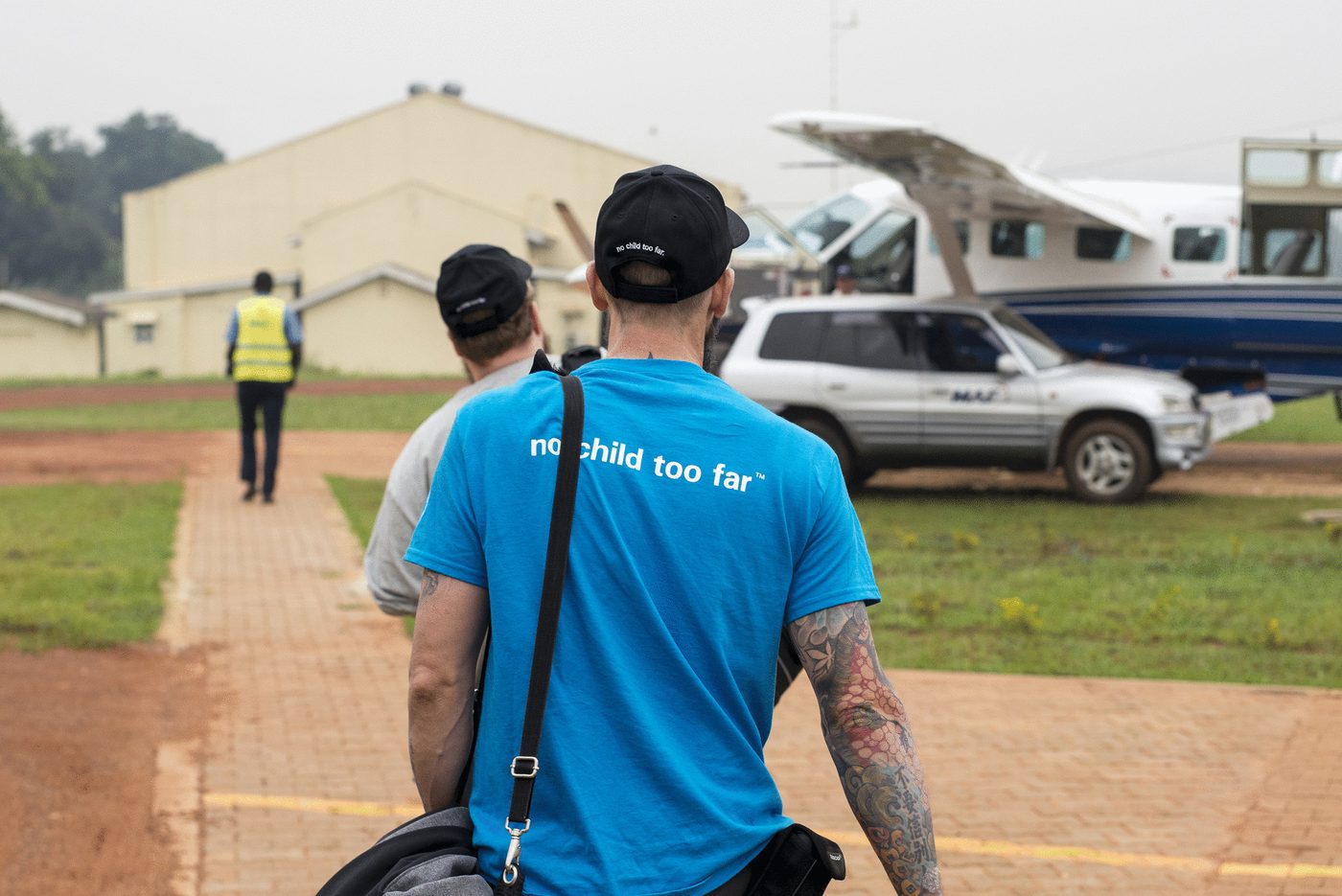 A member of the Idea Studio crew in a UNICEF shirt walking to the aircraft at the Kajjansi airstrip in Kampala