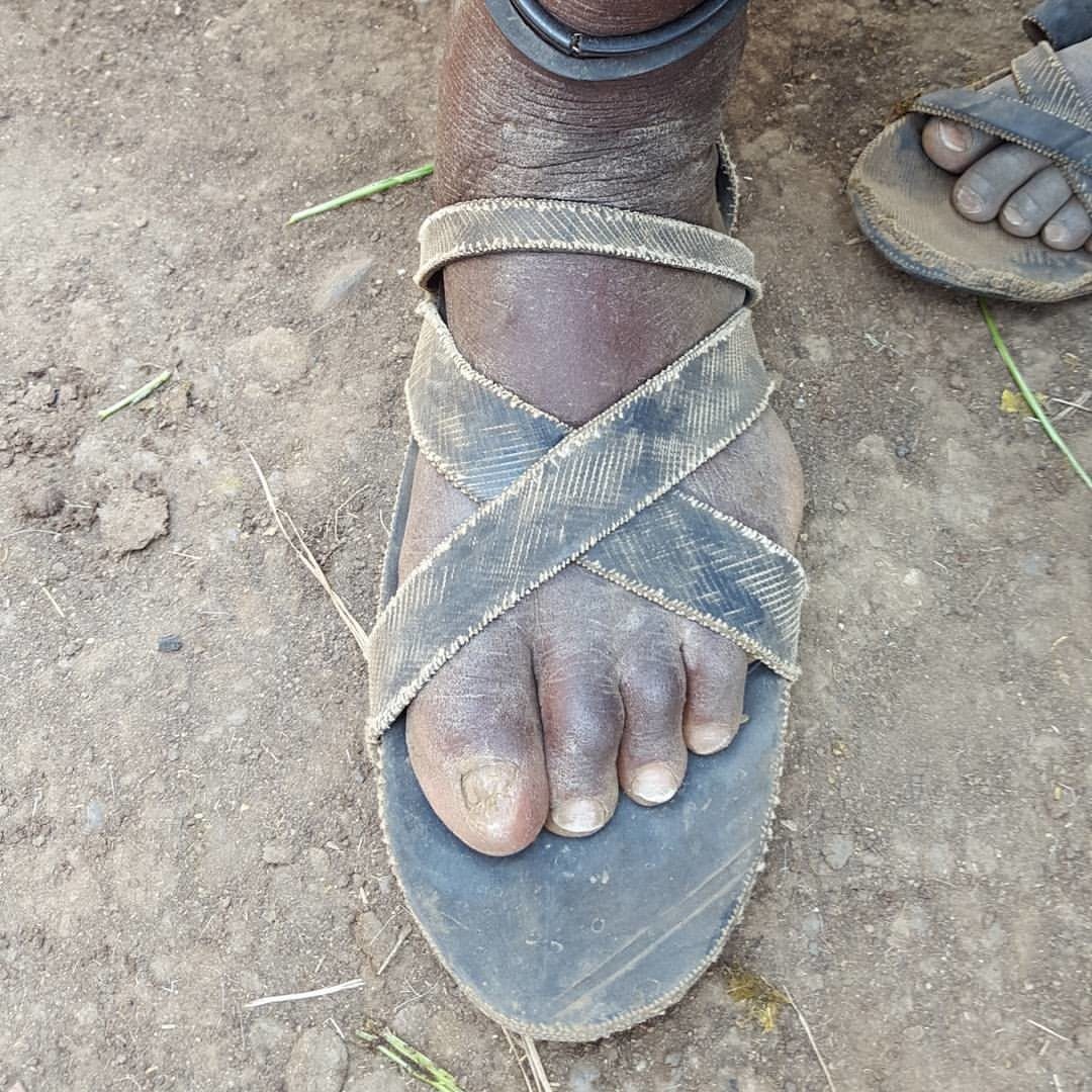 A close-up of a sandal handmade from a recycled rubber tire, worn on a bare foot